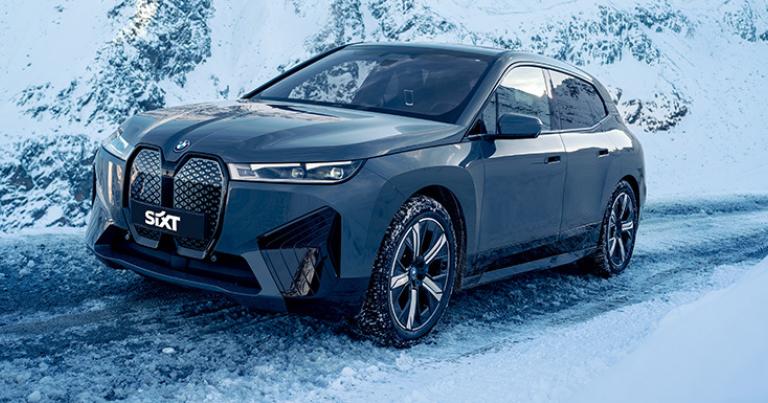 Une BMW iX 100 % électrique louée chez Sixt, dans un paysage de montagne enneigée.